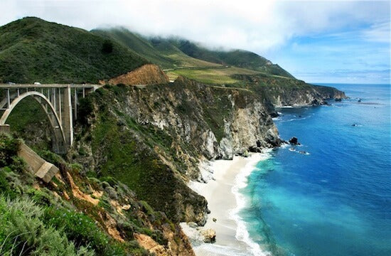 Sweeping view of the mountainous and rocky coastline of Big Sur featuring blue waters and the Bixby Bridge