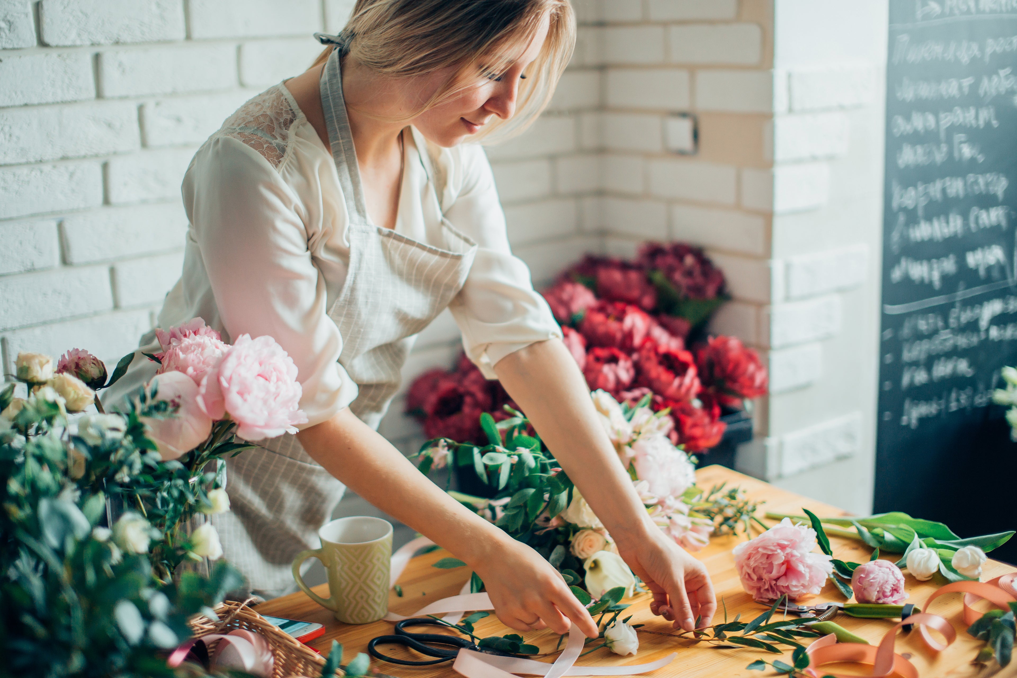 Carmel florist arranging peonies and roses for Valentine's Day arrangements