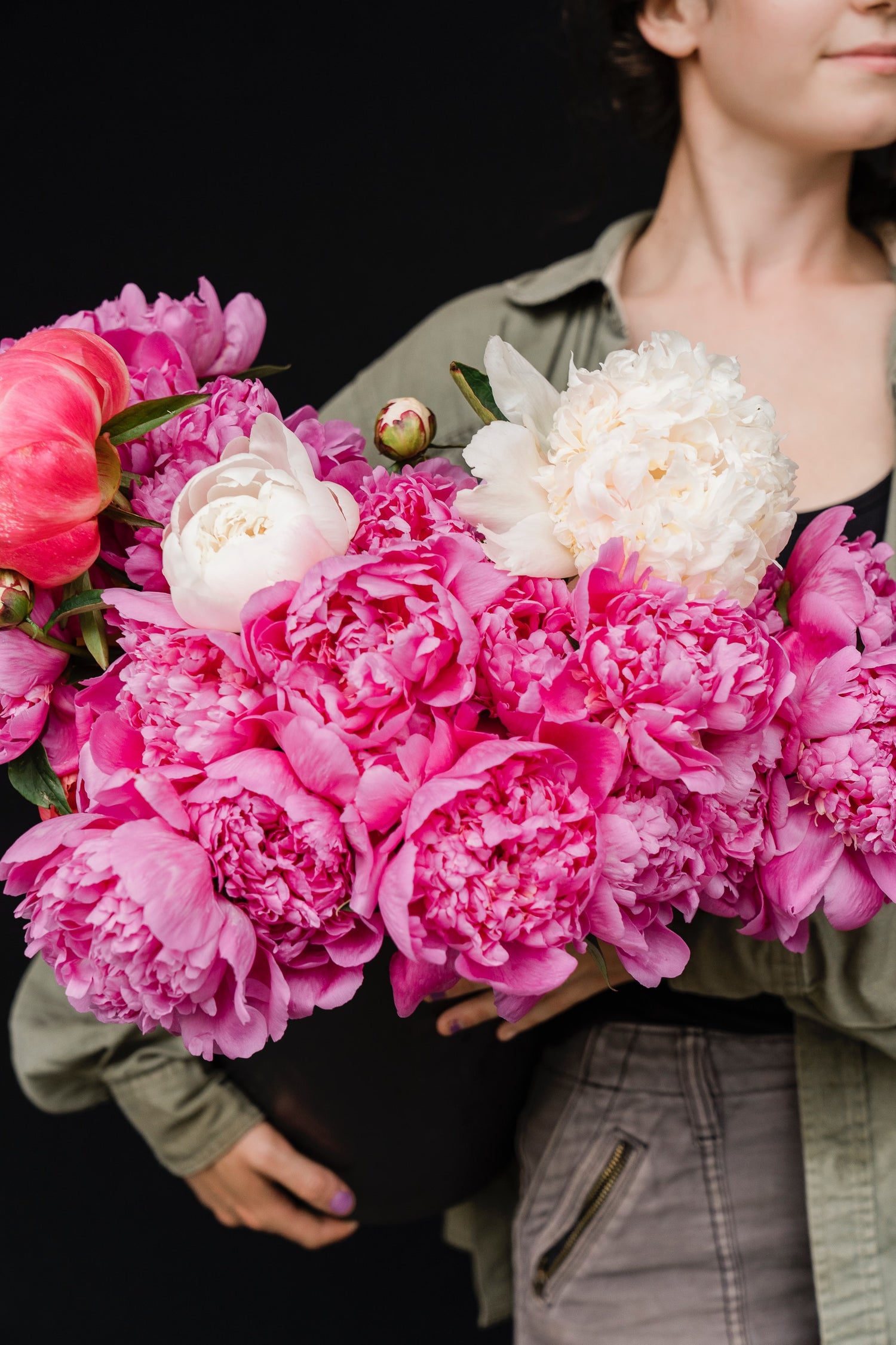 Carmel-by-the-Sea florist holding fresh pink peonies in a bucket