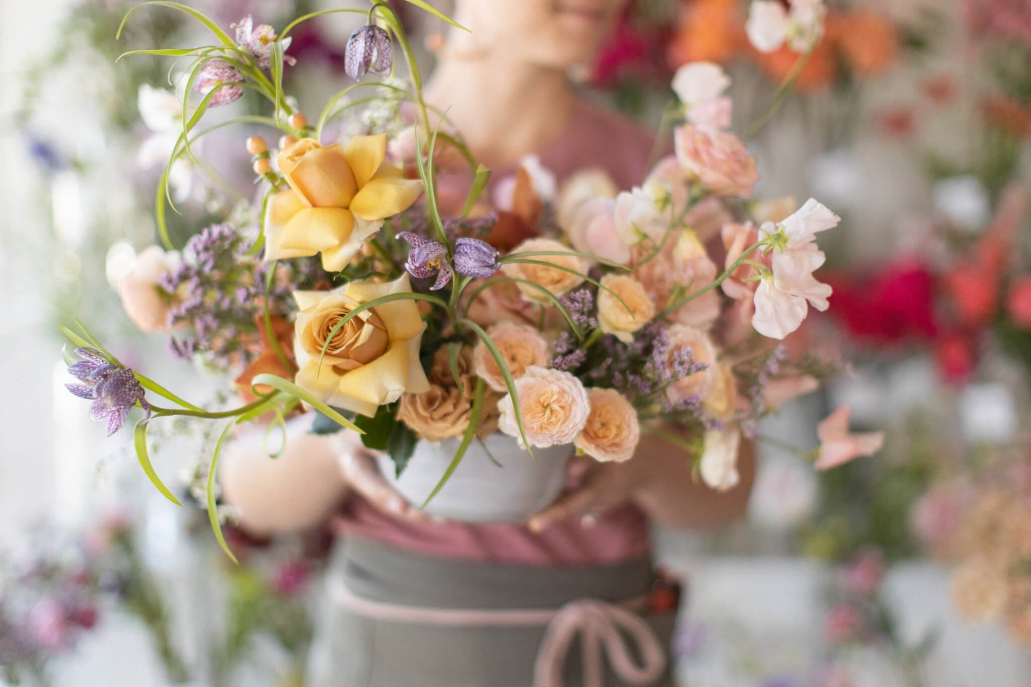 Carmel florist holding a flower arrangement featuring roses and sweet peas