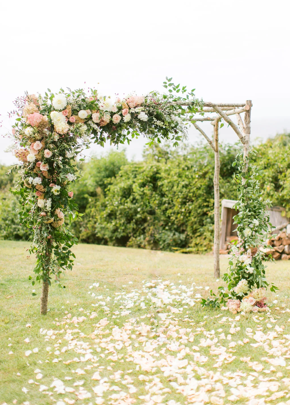 Wedding arch in peach and pink flowers created by Carmel florist for wedding at Carmel Valley Ranch