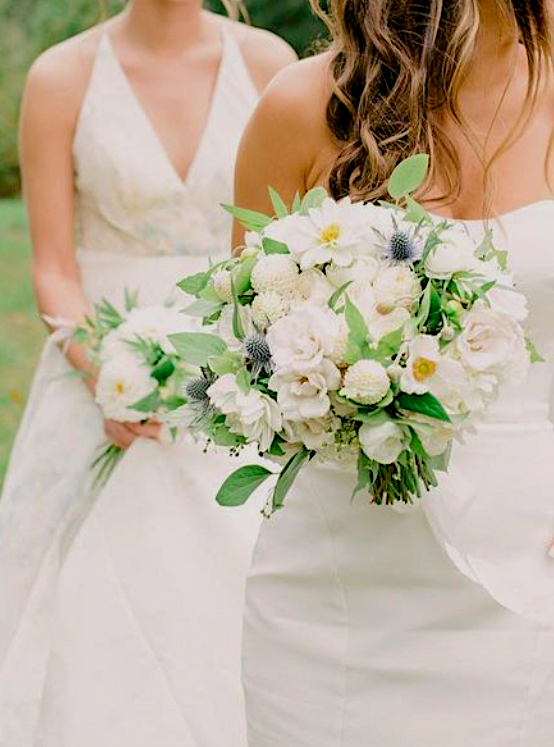 Bride in a strapless white dress carrying a bridal bouquet with white roses, ranunculus, dahlias and poppies