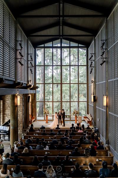 View of bride and groom in front of giant windows looking out at forest at Church in the Forest Pebble Beach 