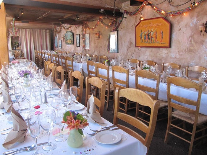 Stone-walled private dining room at Fandango Restaurant set up with long tables covered in fresh linens and vases of flowers