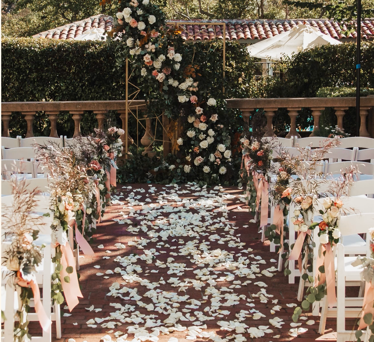 Wedding ceremony set up with aisle rose petals and dramatic rose covered arch