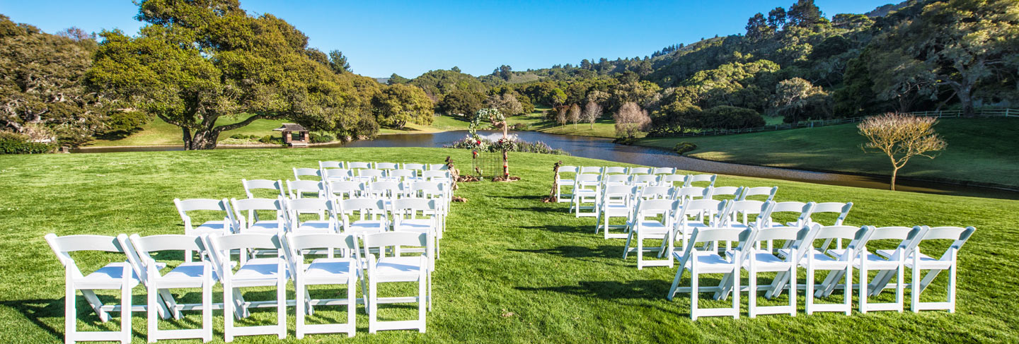 Outdoor wedding set up at Quail Meadows on bright green grass surrounded by oak trees and blue skies
