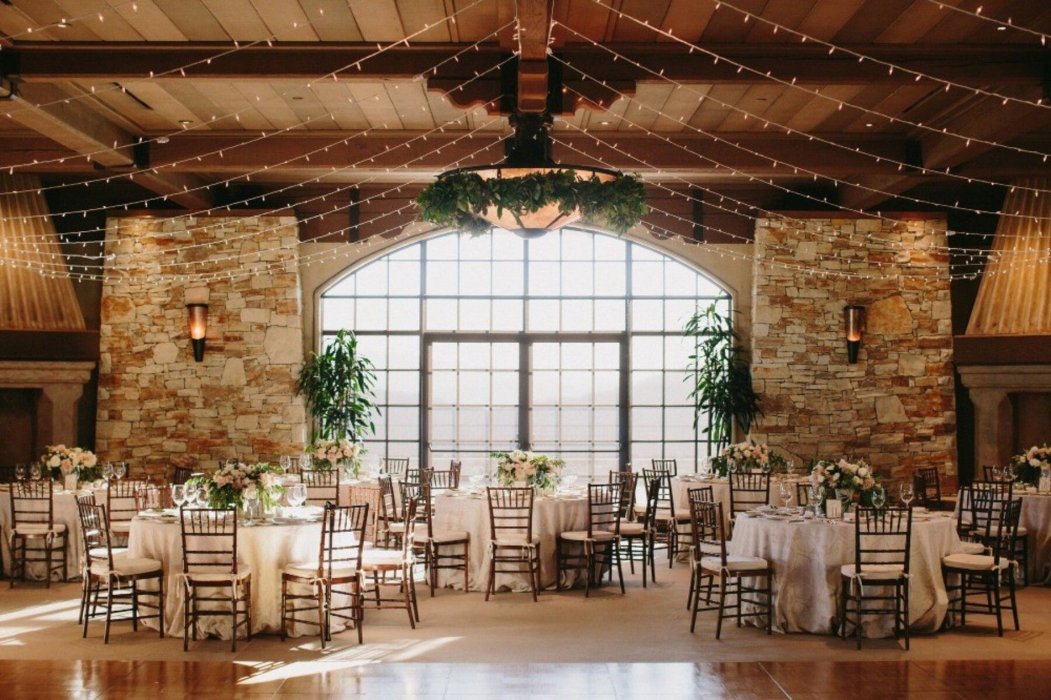 Wedding reception in the vast club house ballroom at Tehama with a floral chandelier and walk in fireplaces
