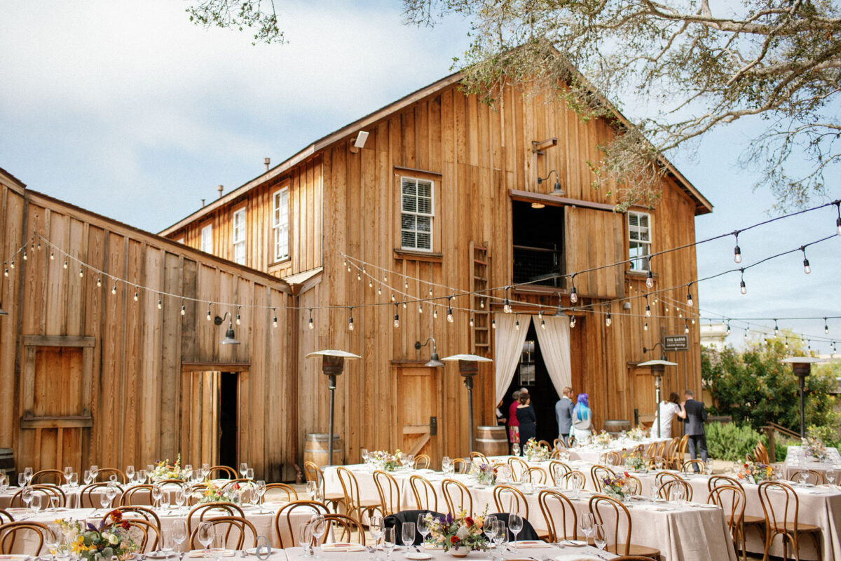Outdoor wedding reception in front of a charming and rustic barn at Cooper Molera in Monterey